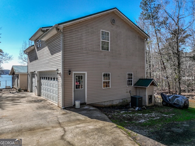 view of property exterior with a garage, driveway, and cooling unit