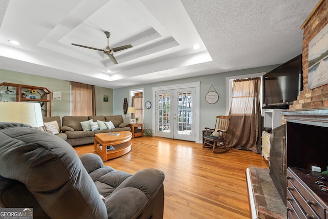 living room with a tray ceiling, french doors, recessed lighting, light wood-style flooring, and a ceiling fan