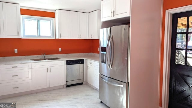 kitchen with stainless steel appliances, white cabinetry, and sink