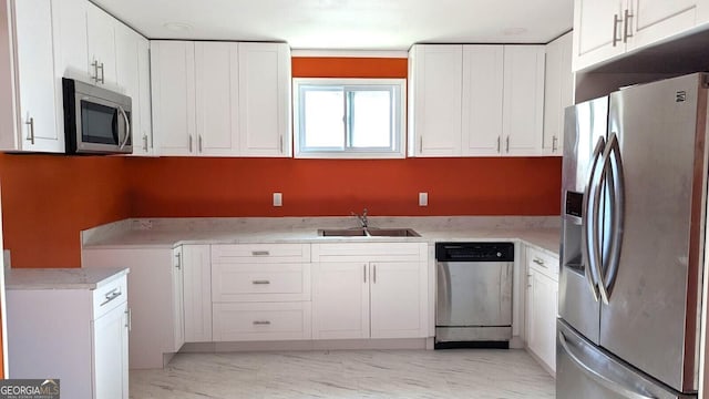 kitchen with stainless steel appliances, ornamental molding, sink, and white cabinets