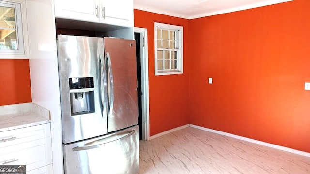 kitchen featuring ornamental molding, stainless steel fridge, light stone countertops, and white cabinets