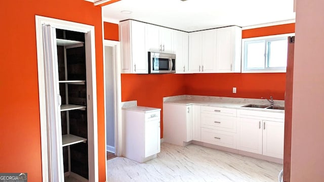 kitchen featuring crown molding, sink, and white cabinets