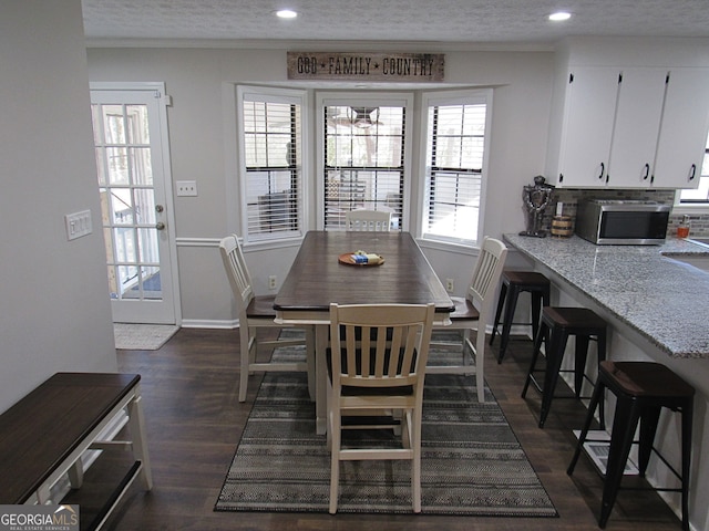 dining room with dark wood-type flooring, ornamental molding, and a textured ceiling