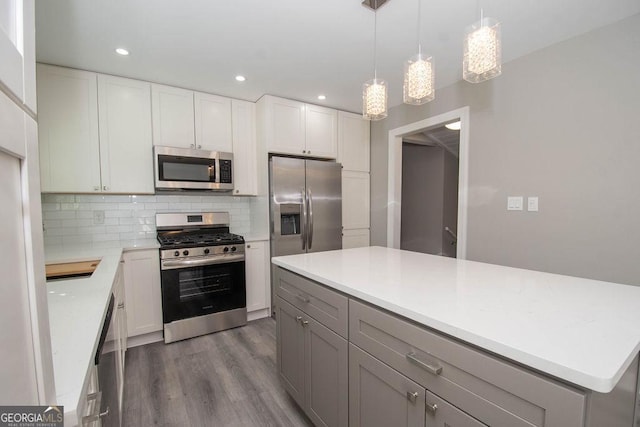 kitchen featuring backsplash, hanging light fixtures, stainless steel appliances, white cabinets, and dark hardwood / wood-style flooring