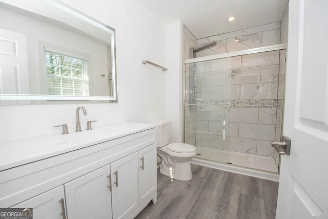 bathroom with vanity, toilet, a shower with shower door, and hardwood / wood-style floors