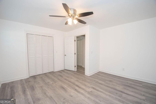 unfurnished bedroom featuring ceiling fan, light hardwood / wood-style floors, and a closet