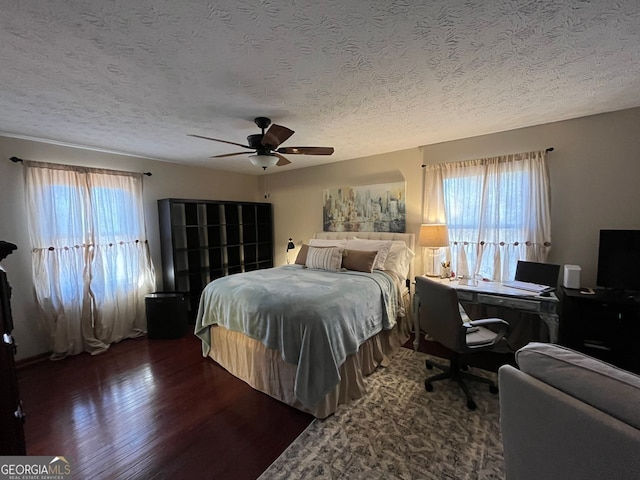 bedroom with multiple windows, a textured ceiling, dark wood-type flooring, and ceiling fan