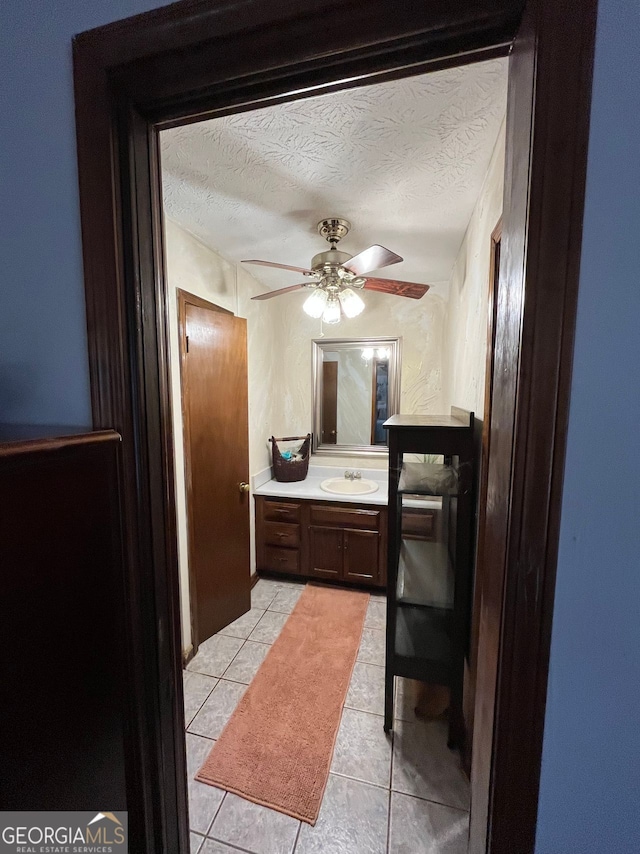 bathroom with ceiling fan, vanity, tile patterned flooring, and a textured ceiling