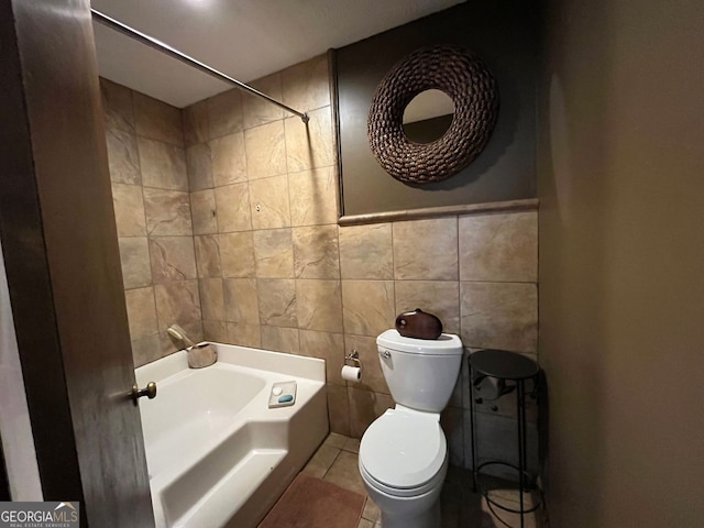 bathroom with toilet, tile patterned flooring, and tile walls