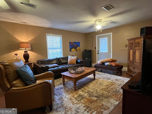 living room with ceiling fan and a textured ceiling