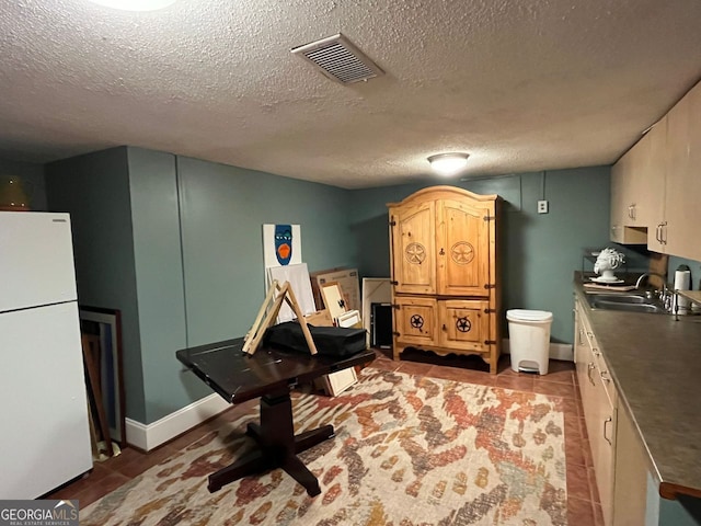 interior space with white refrigerator, sink, and a textured ceiling