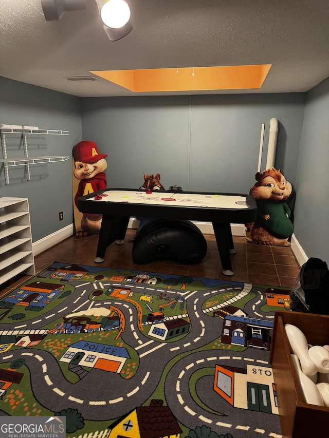 recreation room featuring a textured ceiling