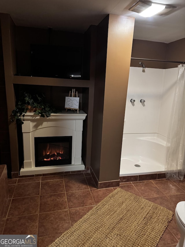 bathroom featuring toilet, tile patterned floors, and a shower with shower curtain