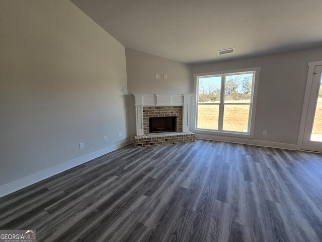 unfurnished living room featuring dark hardwood / wood-style flooring, vaulted ceiling, and a brick fireplace