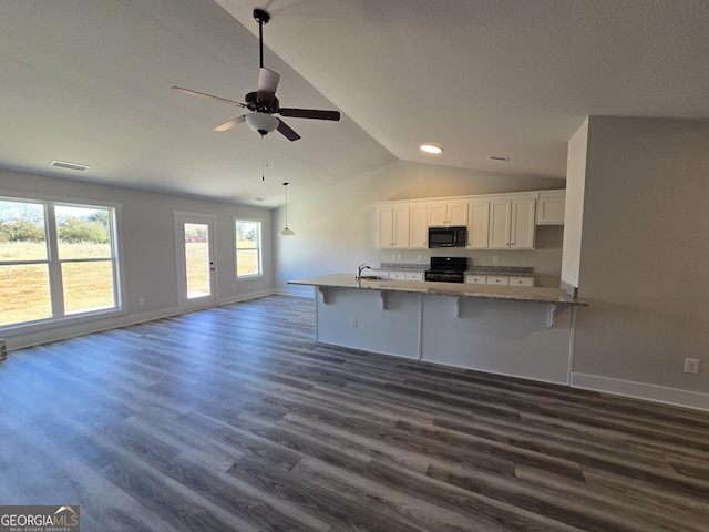 kitchen featuring black appliances, white cabinetry, dark hardwood / wood-style flooring, a kitchen bar, and kitchen peninsula