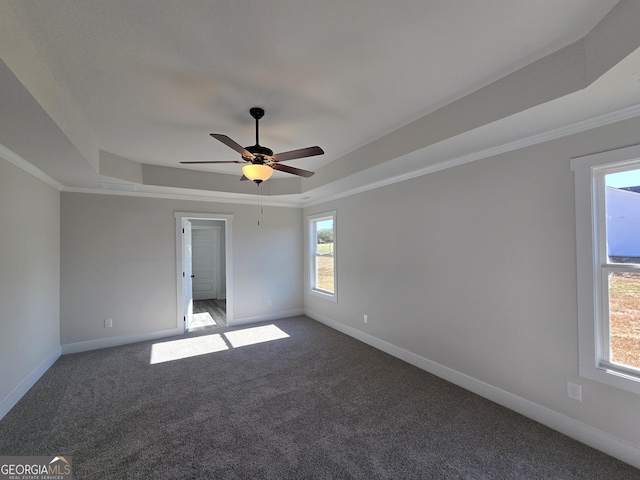 carpeted empty room featuring a tray ceiling, ornamental molding, and ceiling fan