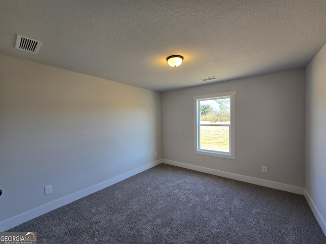 unfurnished room with a textured ceiling and dark colored carpet