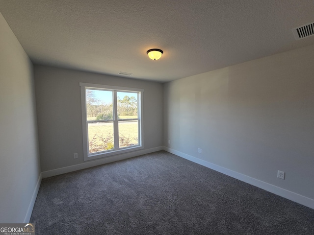 unfurnished room with dark carpet and a textured ceiling