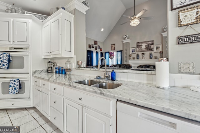 kitchen featuring light tile patterned flooring, lofted ceiling, sink, white appliances, and white cabinets