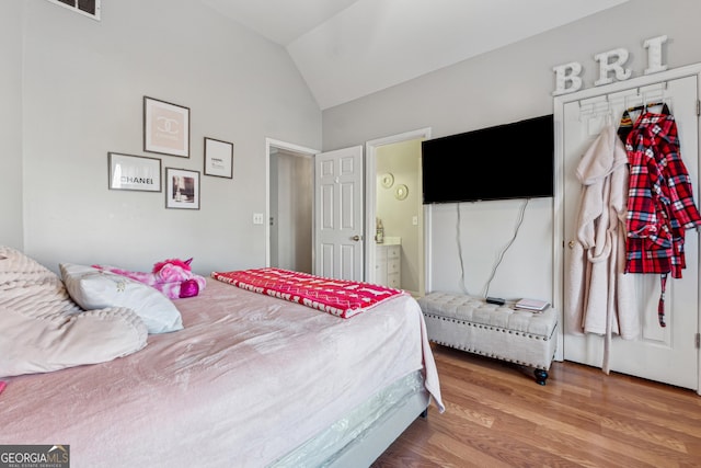 bedroom featuring a closet, ensuite bathroom, vaulted ceiling, and wood-type flooring