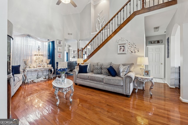 living room featuring ceiling fan, hardwood / wood-style floors, and a towering ceiling