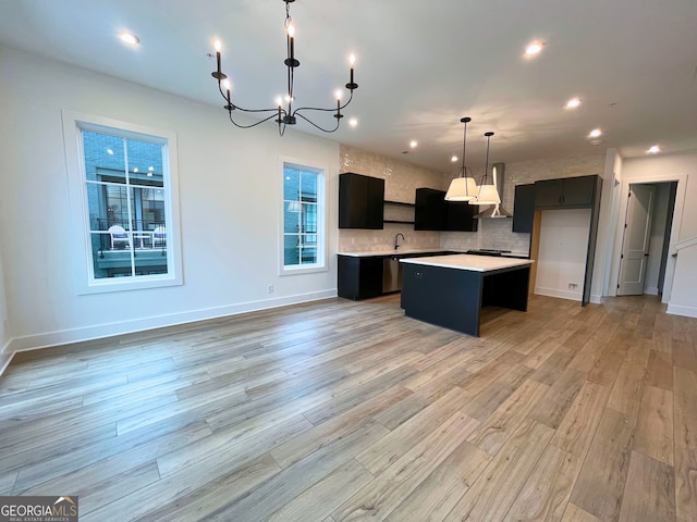 kitchen with light hardwood / wood-style flooring, backsplash, a center island, decorative light fixtures, and wall chimney exhaust hood