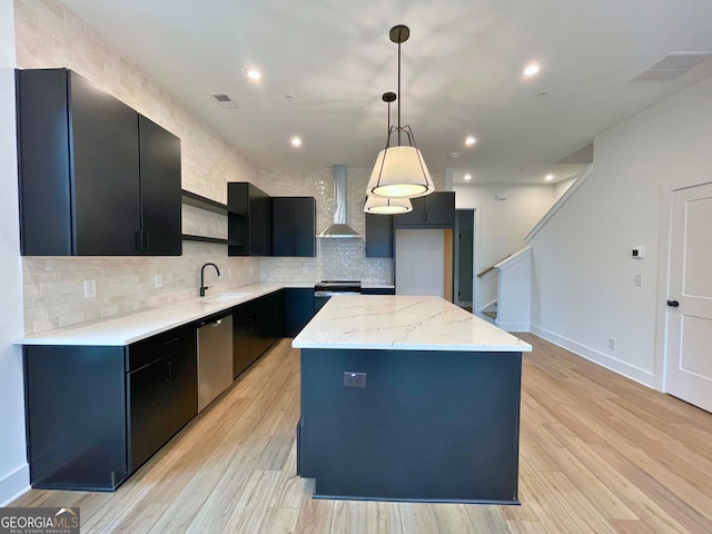 kitchen with a kitchen island, pendant lighting, stainless steel dishwasher, light hardwood / wood-style floors, and wall chimney range hood