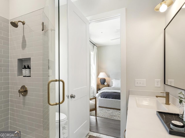 bathroom with vanity, hardwood / wood-style flooring, a shower with door, and toilet