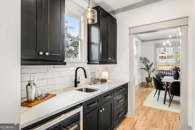 kitchen featuring sink, pendant lighting, wine cooler, and light stone counters