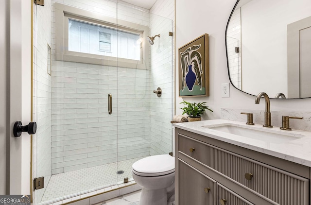 bathroom featuring vanity, toilet, and a shower with shower door