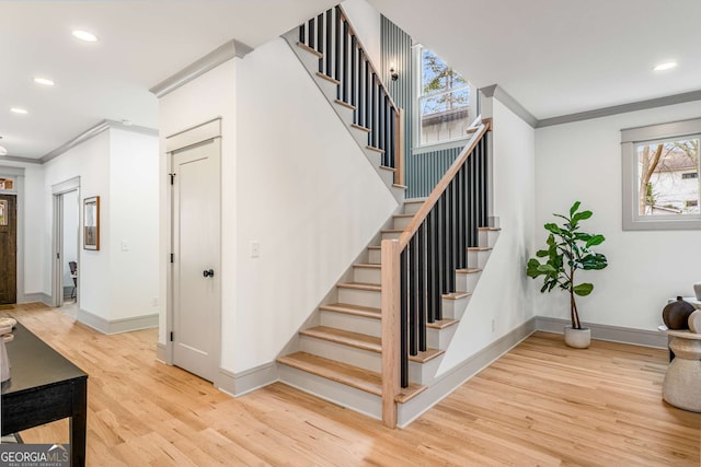 staircase with ornamental molding and hardwood / wood-style floors