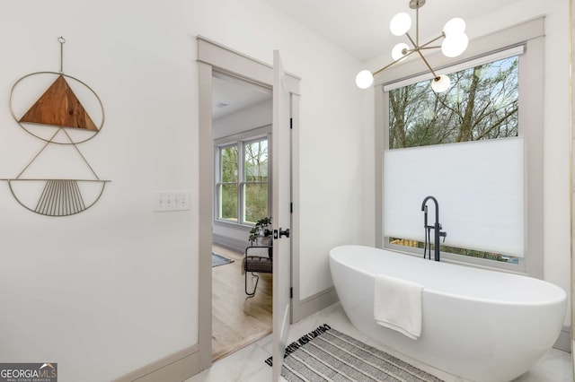 bathroom with a notable chandelier and a bathtub