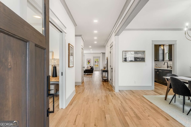 corridor with sink and light hardwood / wood-style flooring