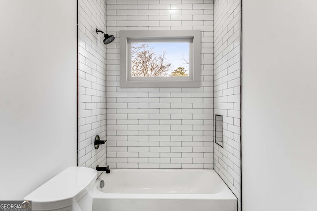 bathroom featuring tiled shower / bath combo and toilet