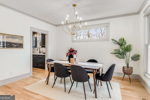 dining room featuring crown molding, sink, a notable chandelier, and light hardwood / wood-style floors