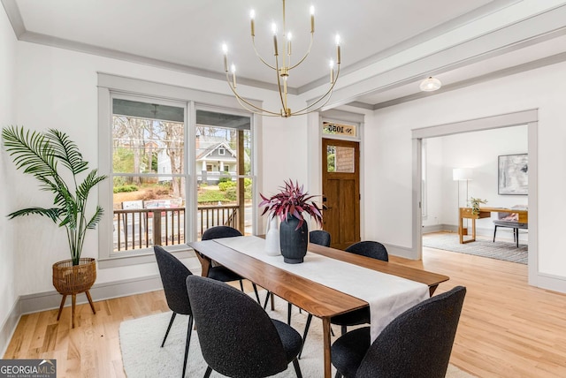 dining area featuring a notable chandelier, ornamental molding, and light wood-type flooring