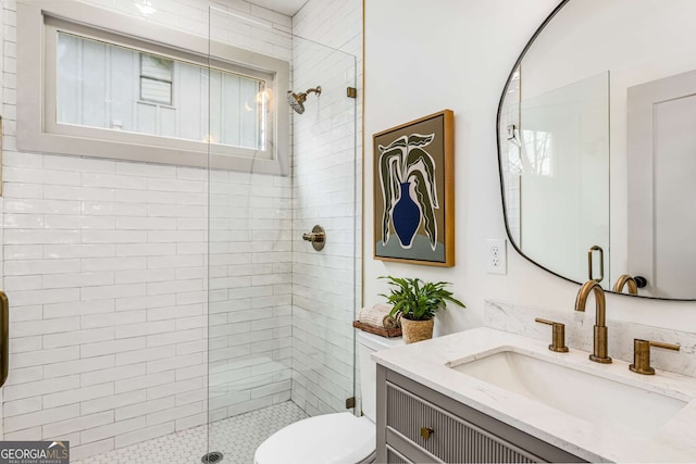 bathroom with vanity, toilet, and a tile shower