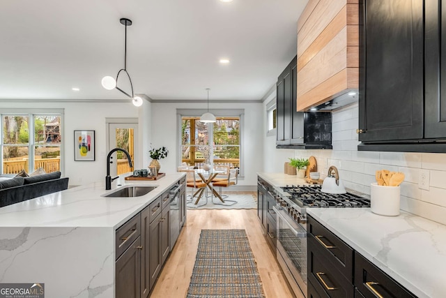 kitchen featuring pendant lighting, sink, light stone counters, tasteful backsplash, and high end stainless steel range