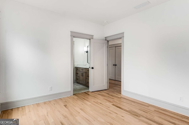 unfurnished bedroom with connected bathroom and light hardwood / wood-style flooring