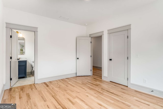 unfurnished bedroom with ensuite bath and light hardwood / wood-style floors