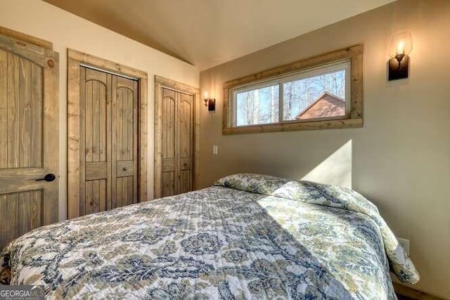 bedroom with vaulted ceiling and two closets