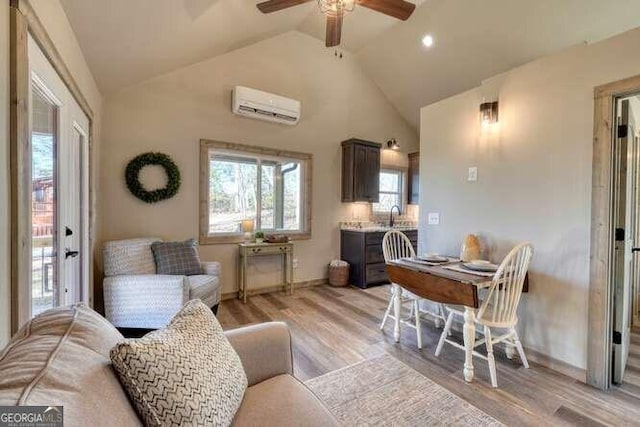 living room featuring an AC wall unit, sink, lofted ceiling, and light hardwood / wood-style floors