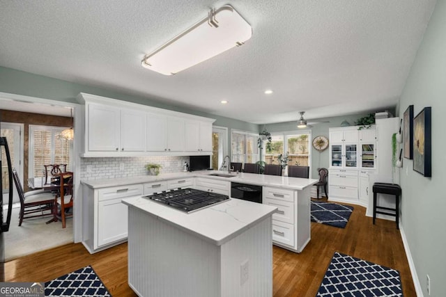 kitchen featuring stainless steel gas stovetop, white cabinetry, a kitchen island, and black dishwasher