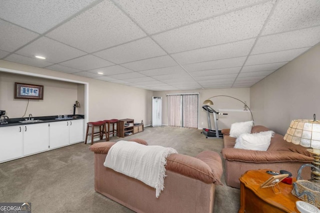 living room with light colored carpet, a paneled ceiling, and sink