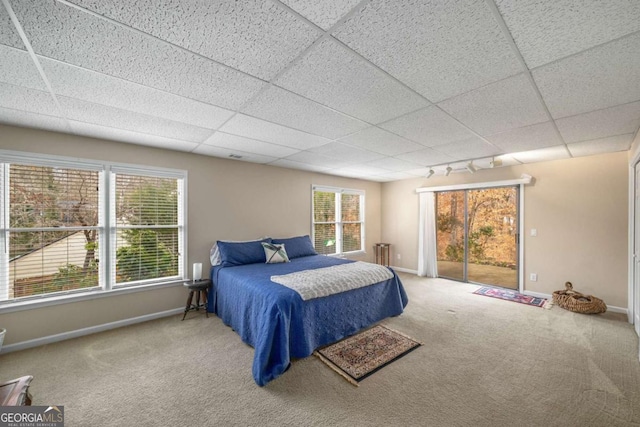 bedroom featuring track lighting, a drop ceiling, carpet, and access to outside