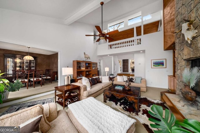 living room featuring a fireplace, beamed ceiling, carpet floors, a high ceiling, and ceiling fan