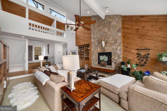 living room featuring a stone fireplace, beamed ceiling, and wood walls