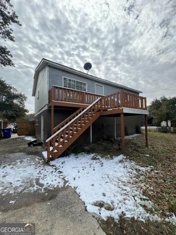 snow covered rear of property with a deck