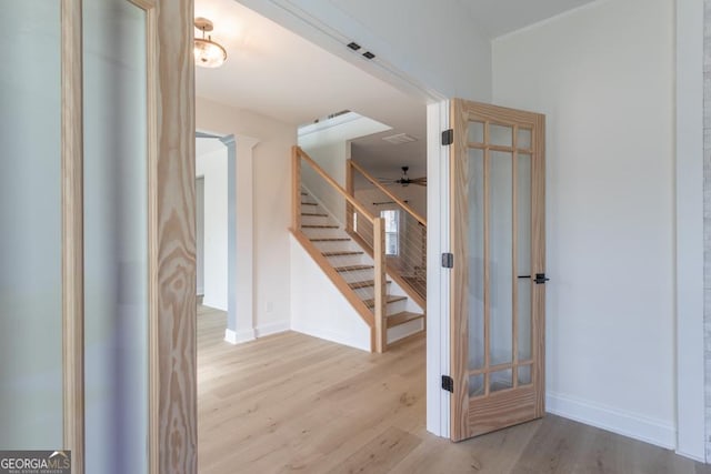 stairway featuring ceiling fan, decorative columns, baseboards, and wood finished floors