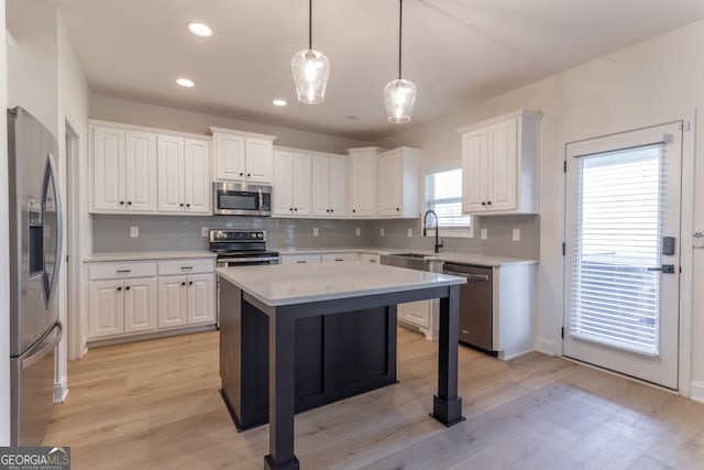 kitchen with stainless steel appliances, light countertops, white cabinetry, and a sink